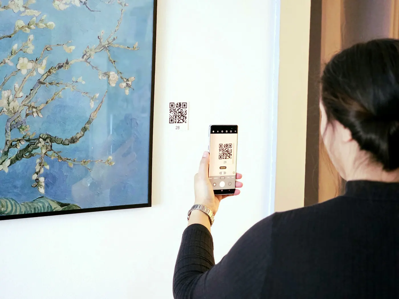 Museumsbesucherin scannt mit dem Smartphone einen QR-Code an einem Exponat